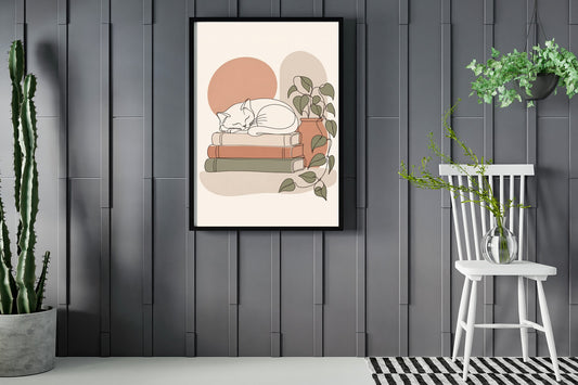 Cat asleep on a stack of books, line art print framed in a room with plants