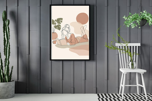 Woman lying down reading a book, line art print framed in a room with plants