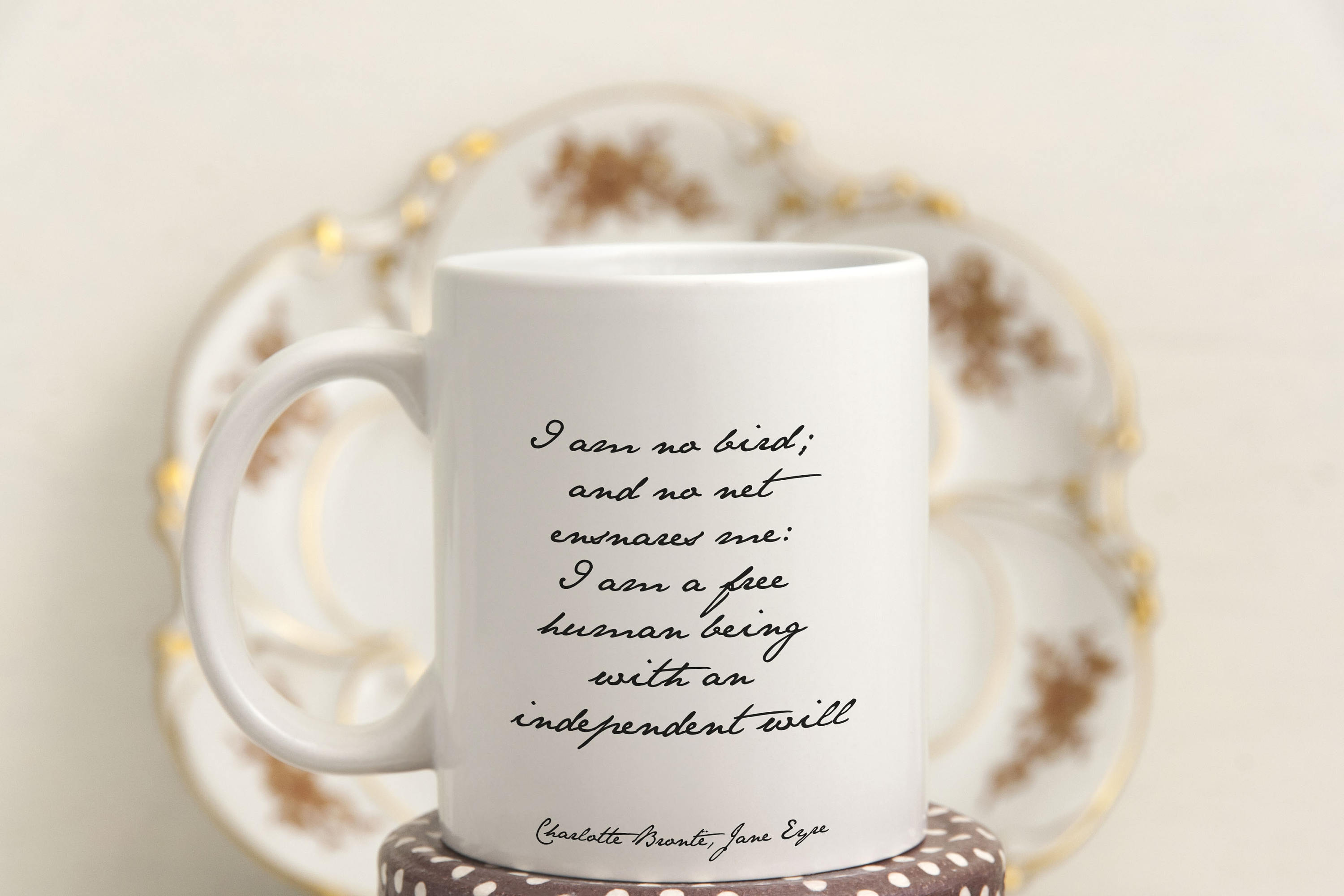 May include: A white coffee mug with a black quote that reads 'I am no bird; and no net ensnares me: I am a free human being with an independent will - Charlotte Bronte, Jane Eyre'.