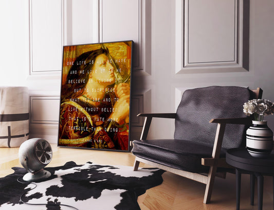 A framed print of a vintage painting with white text is propped against a white wall, next to a dark leather armchair and a small side table.