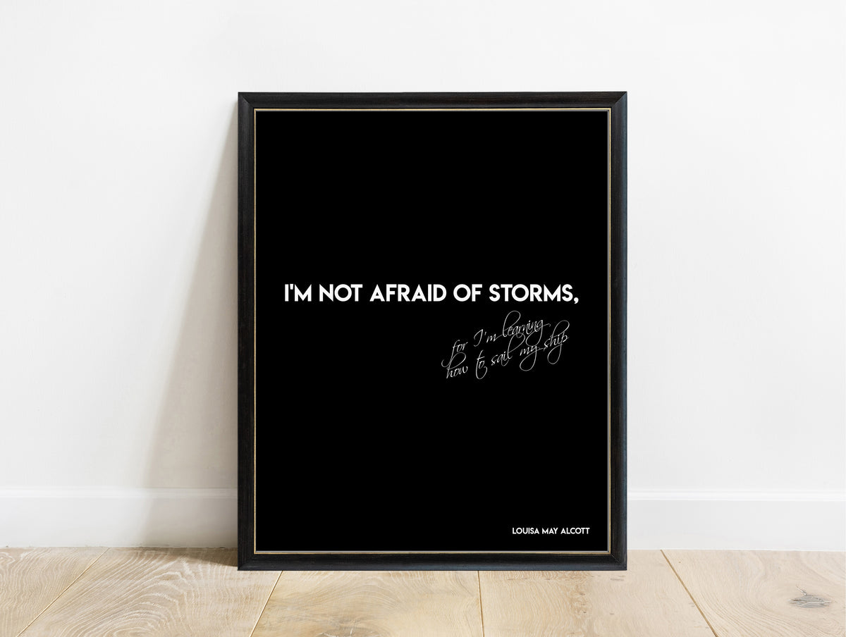 Louisa May Alcott not afraid of storms bold script quote print in a black frame, black background