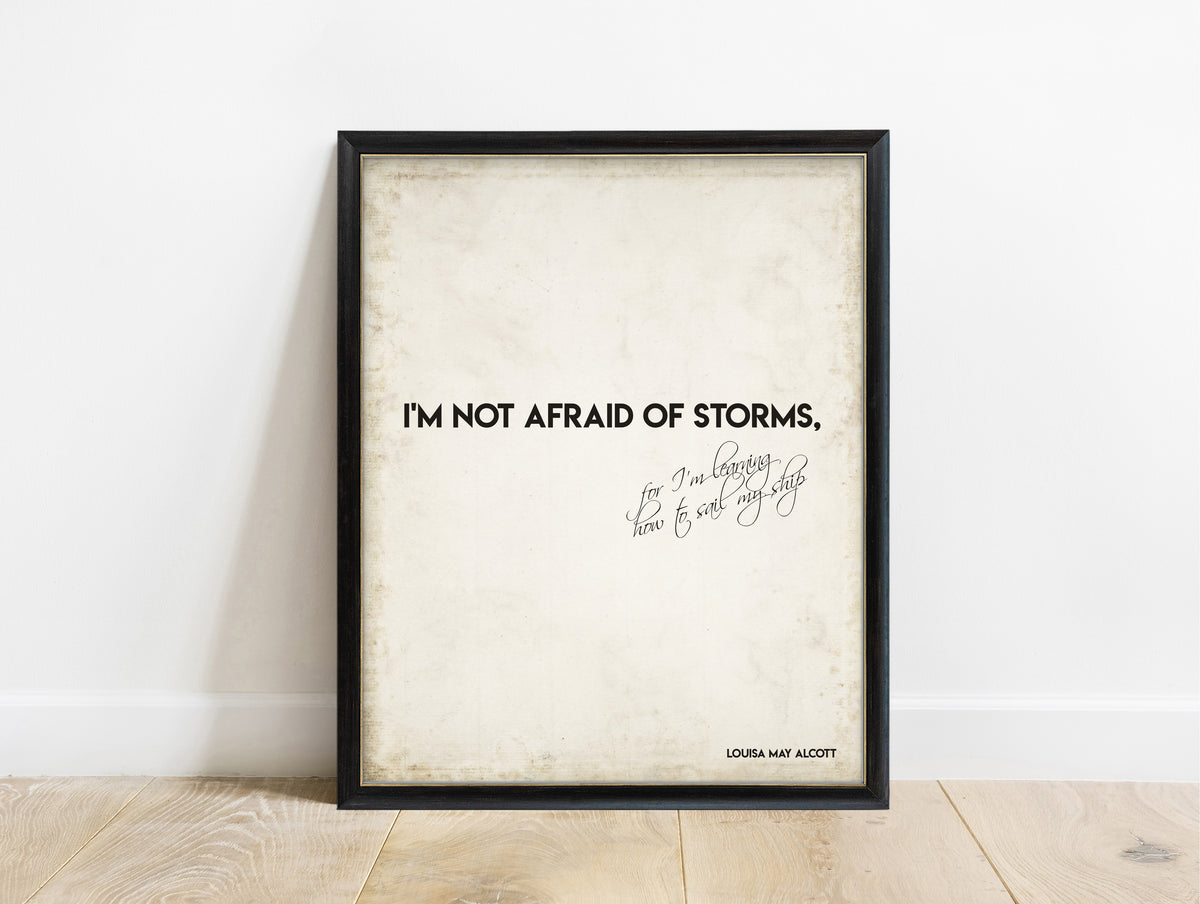 Louisa May Alcott not afraid of storms bold script quote print in a black frame, vintage background