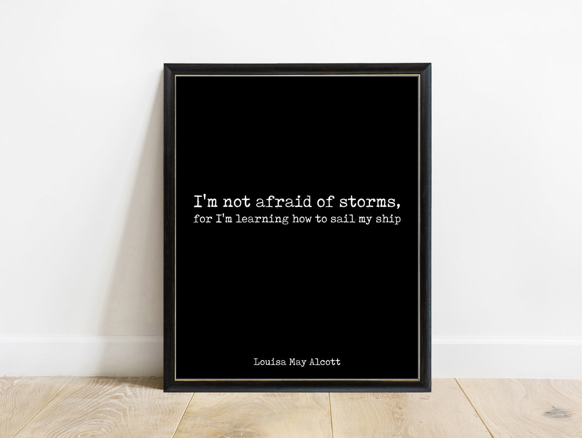 Louisa May Alcott not afraid of storms minimalist typewriter quote print in a black frame, black background