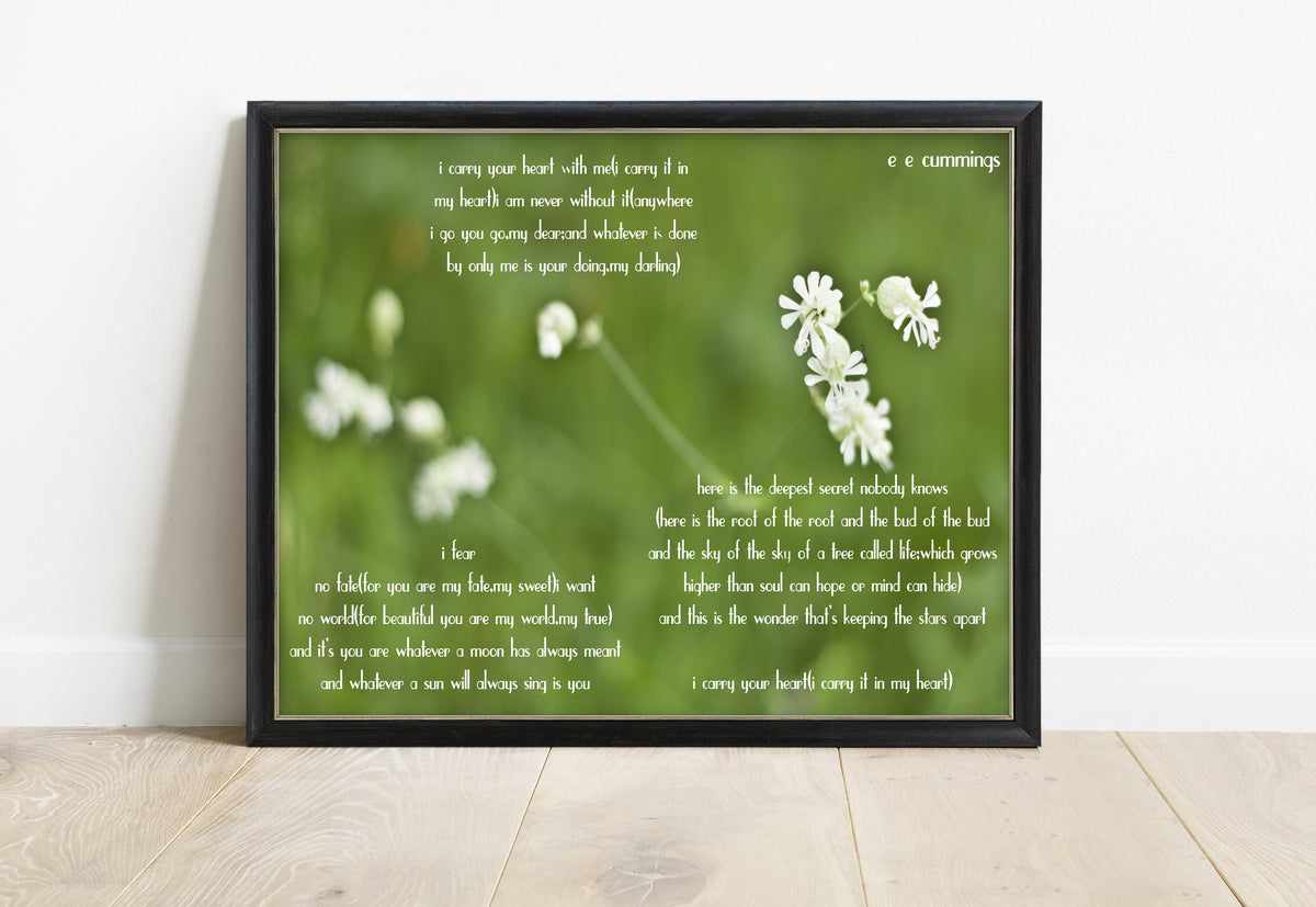 E E Cummings i carry your heart full poem over a photograph of small white wild flowers on green, in a black frame
