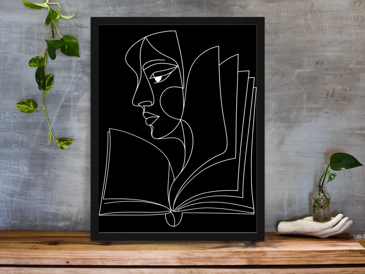 Abstract face in profile flowing into an open book, line art print, white lines on black, framed on a desk