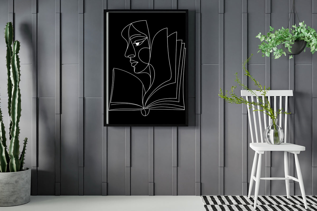 Abstract face in profile flowing into an open book, line art print, white lines on black, framed in a room with plants