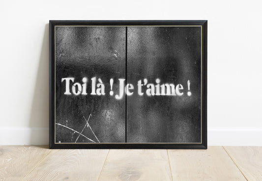 Toi là je t'aime stencilled in white on black doors in Paris, street art photograph, in a black frame
