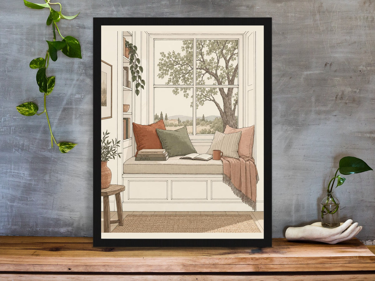 Window seat reading nook with books and a tree view illustration print framed on a desk