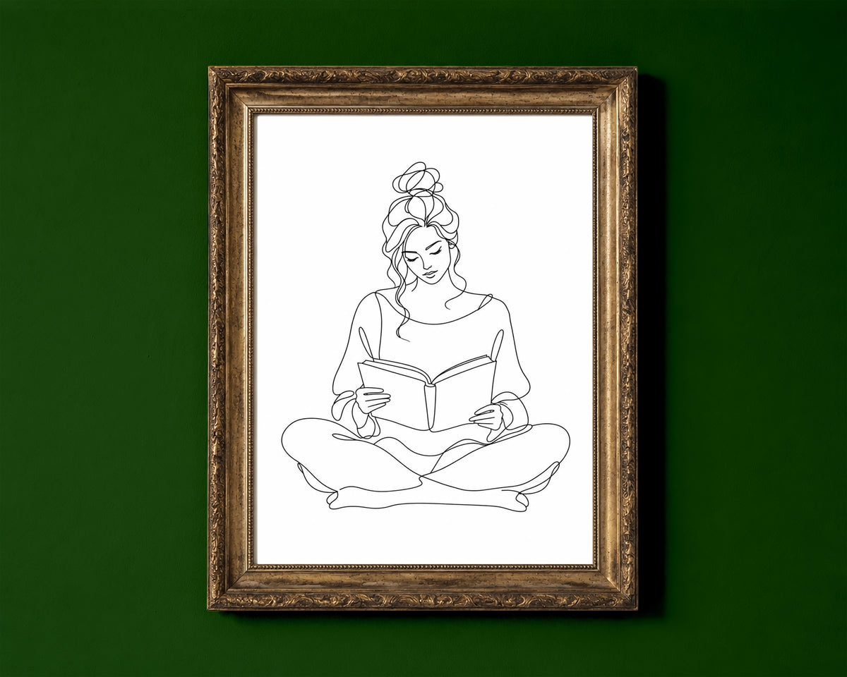 Woman sitting cross-legged reading a book, continuous line art print, black lines on white, shown in a gold frame for display only; framed prints are sent in a black frame