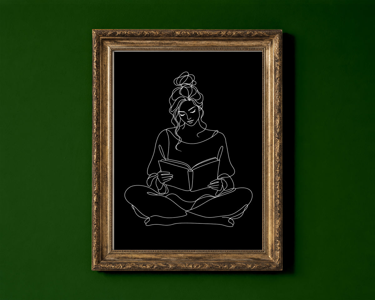 Woman sitting cross-legged reading a book, continuous line art print, white lines on black, shown in a gold frame for display only; framed prints are sent in a black frame