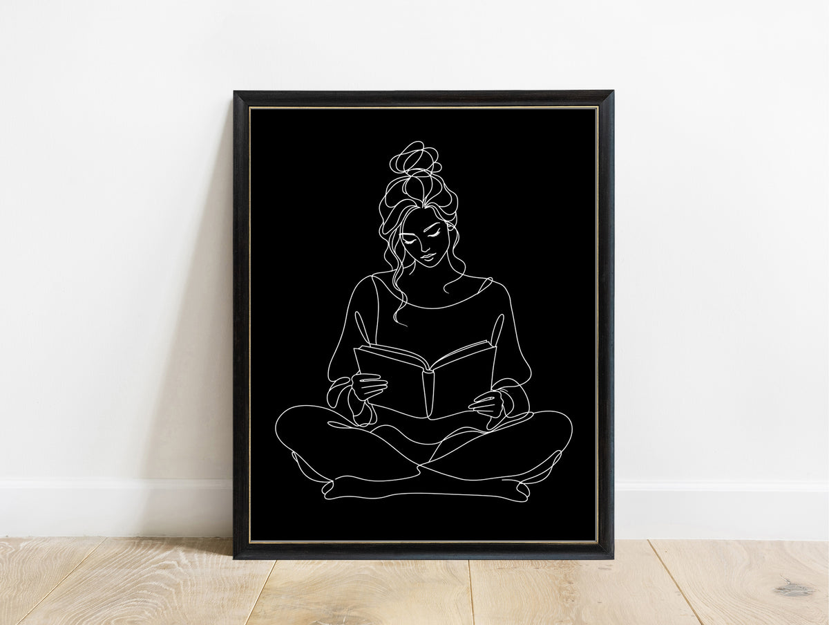 Woman sitting cross-legged reading a book, continuous line art print, white lines on black, in a black frame