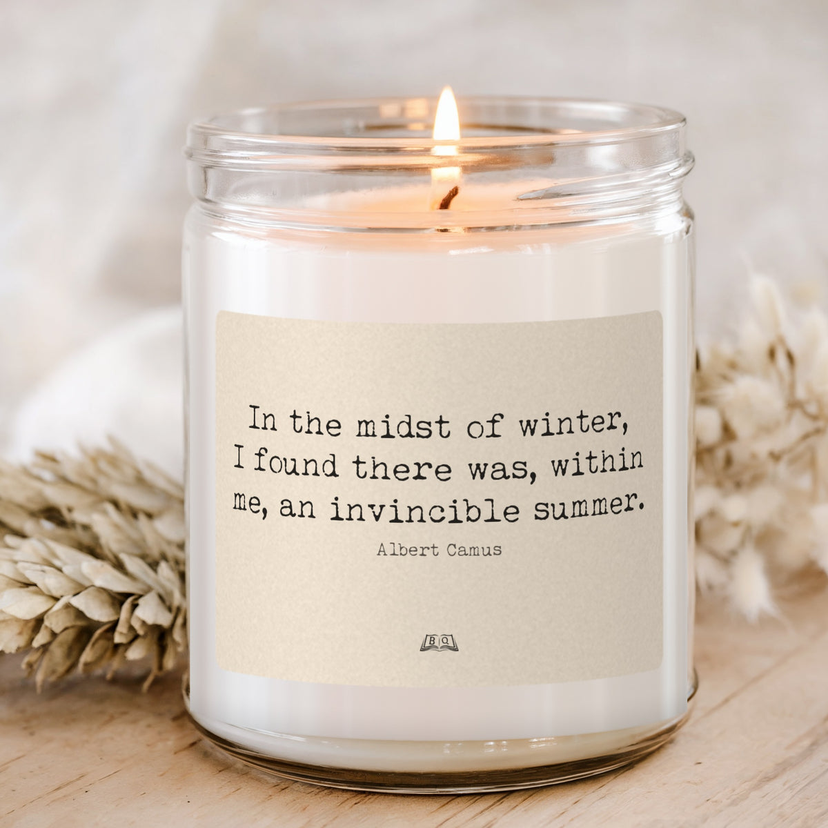 Lit soy candle in a glass jar with the Albert Camus In the midst of winter, an invincible summer label