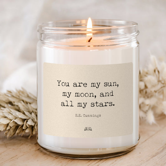 Lit soy candle in a glass jar with the E.E. Cummings You are my sun, my moon label