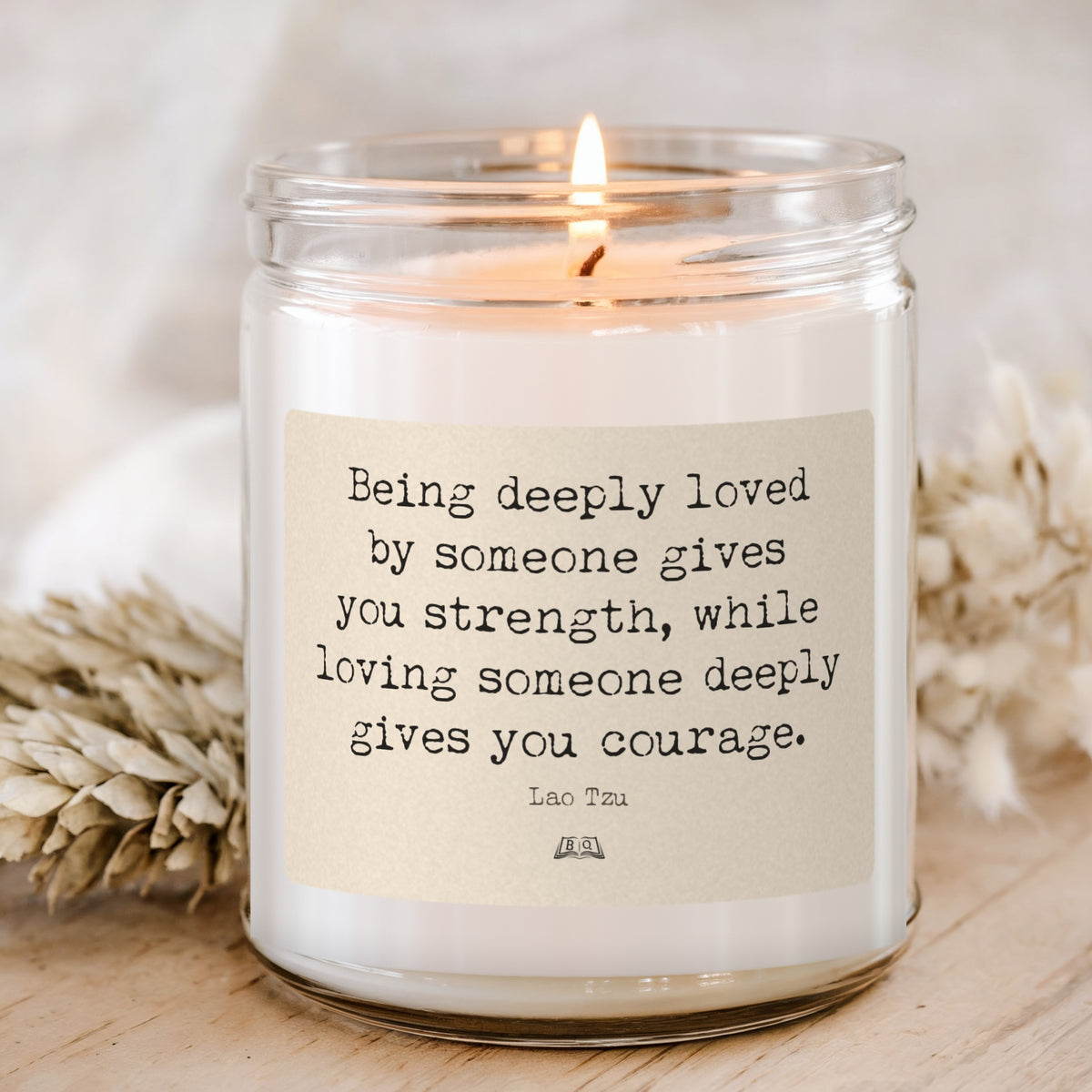 Lit soy candle in a glass jar with the Lao Tzu Being deeply loved by someone gives you strength label
