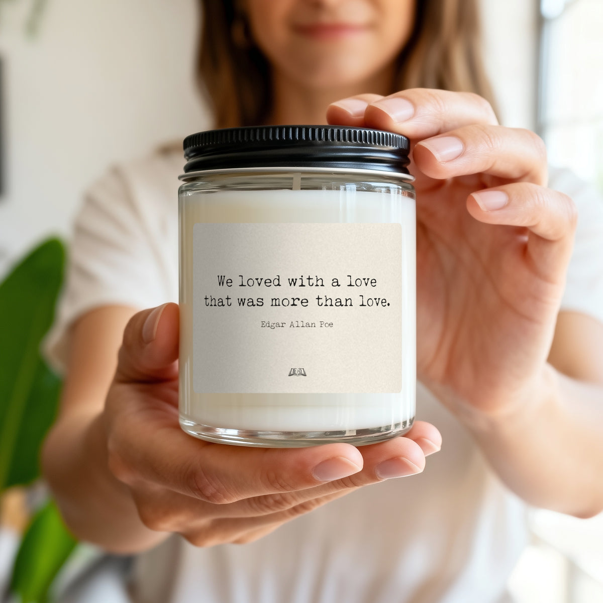 Woman holding a soy candle with the Edgar Allan Poe We loved with a love label, showing its size