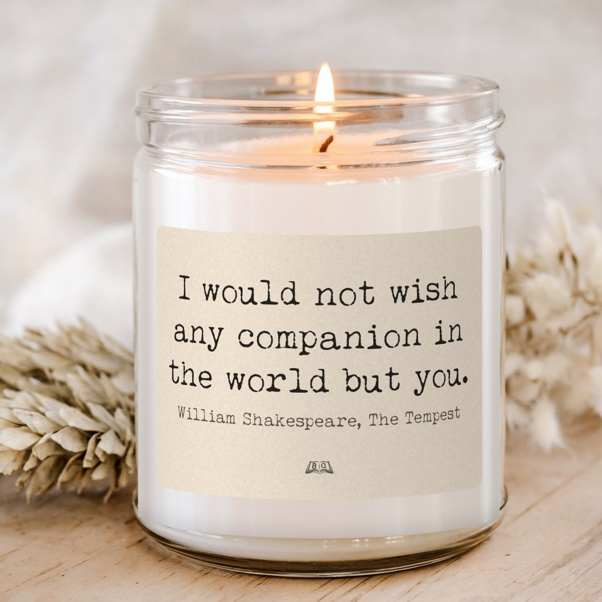 Lit soy candle in a glass jar with the Shakespeare The Tempest I would not wish any companion in the world but you label