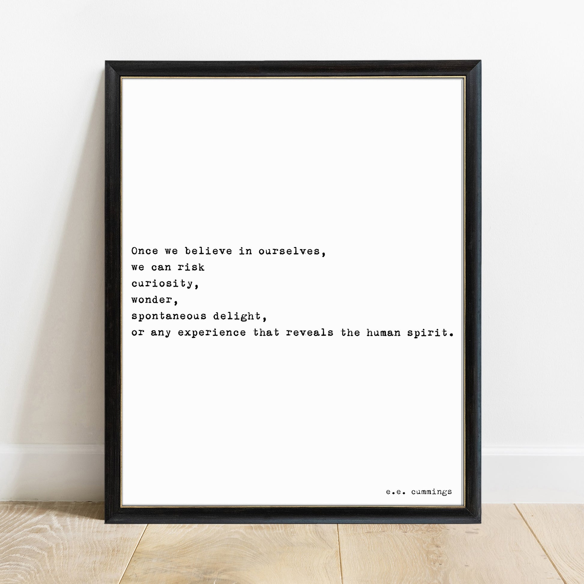 E.E. Cummings once we believe in ourselves quote print in a black frame, white background