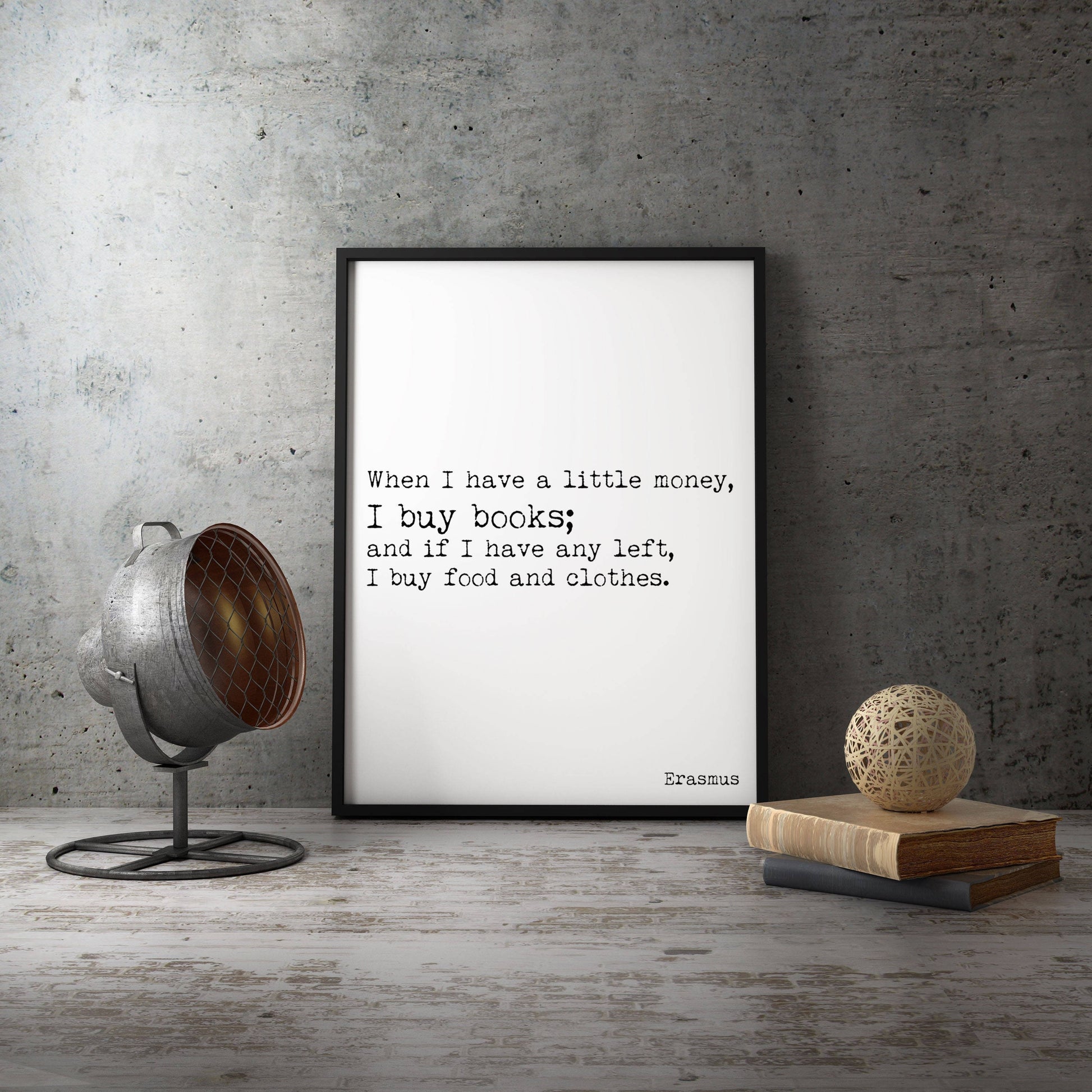 May include: A black framed print with a white background and black text. The text reads 'When I have a little money, I buy books; and if I have any left, I buy food and clothes. Erasmus'.