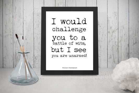 May include: A black framed print with a white background and black text that reads 'I would challenge you to a battle of wits, but I see you are unarmed!' The text is in a typewriter font. The text is attributed to 'William Shakespeare'.