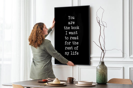 May include: A black framed print with white text that reads 'You are the book I want to read for the rest of my life'.