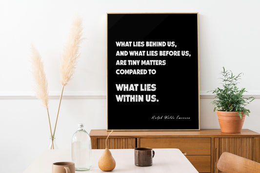 May include: A framed black and gold print featuring the quote "WHAT LIES BEHIND US, AND WHAT LIES BEFORE US, ARE TINY MATTERS COMPARED TO WHAT LIES WITHIN US." by Ralph Waldo Emerson. The print is displayed on a wooden cabinet.