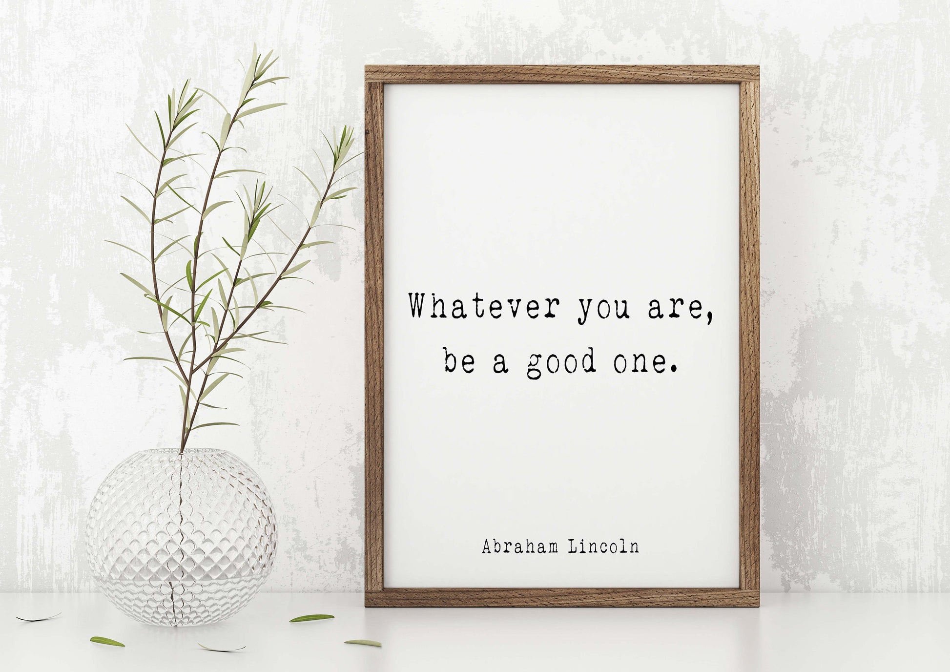 May include: A framed print with a white background and black text that reads "Whatever you are, be a good one." The text is attributed to Abraham Lincoln. The frame is brown wood.