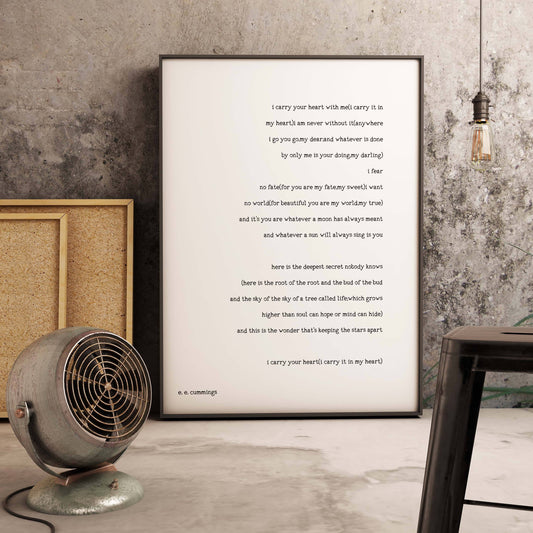 May include: A black and white print of a poem by e. e. cummings titled "i carry your heart with me". The poem is printed on a white background with black text. The poem is framed and hanging on a wall.