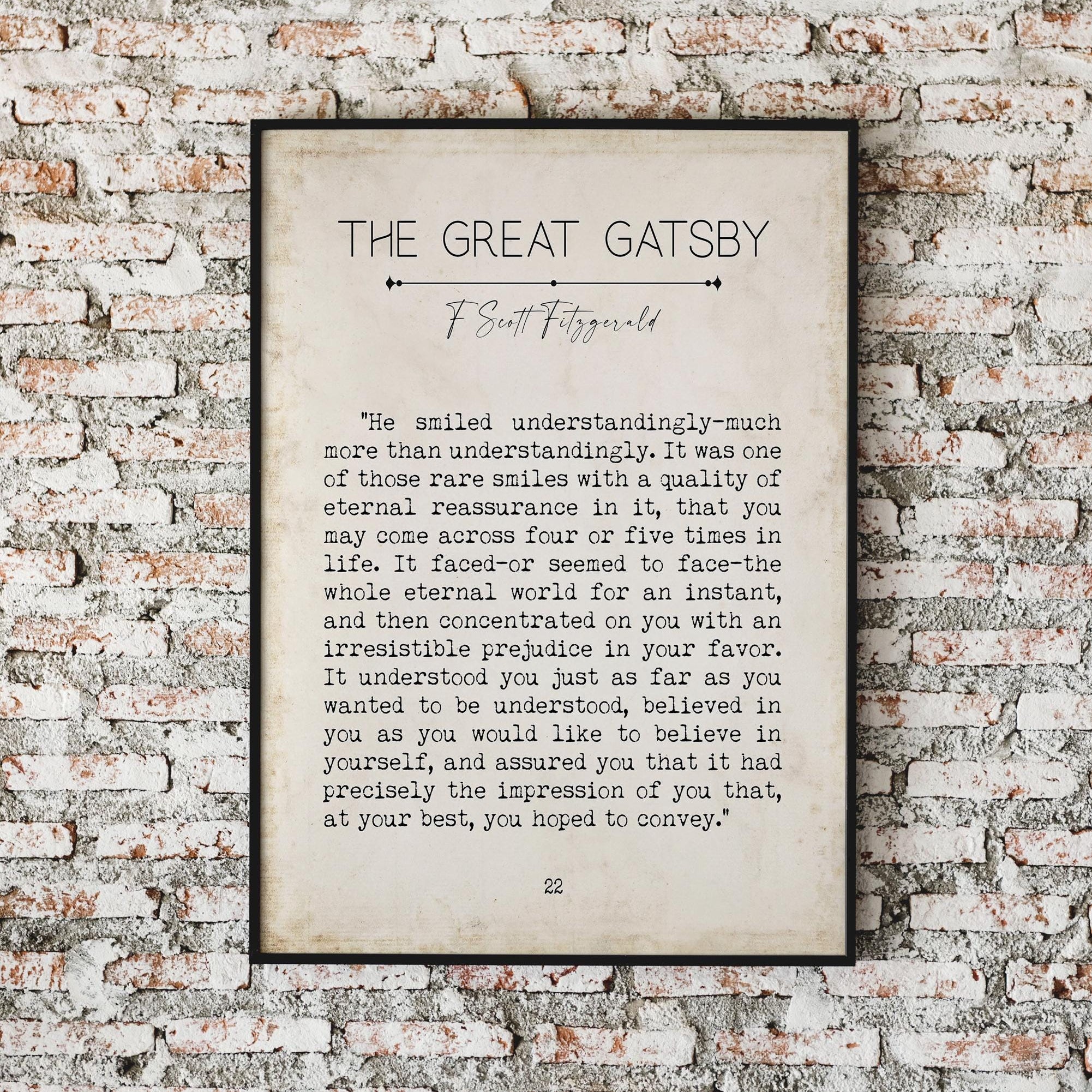 A framed print of a "The Great Gatsby" quote on a brick wall, with text reading: "He smiled understandingly-much more than understandingly. It was one of those rare smiles with a quality of eternal reassurance in it, that you may come across four or