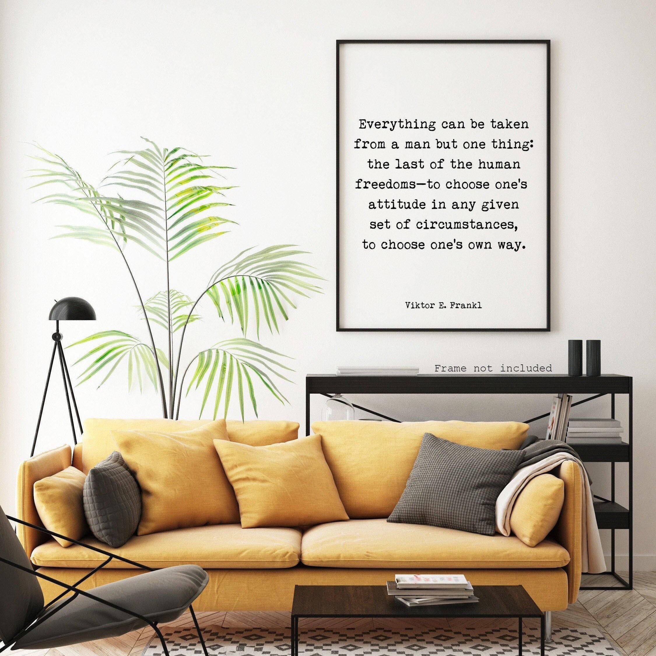 A white print with black text, "Everything can be taken from a man but one thing: the last of the human freedoms—to choose one's attitude in any given set of circumstances, to choose one's own way. Viktor E. Frankl," hangs on a white wall above a