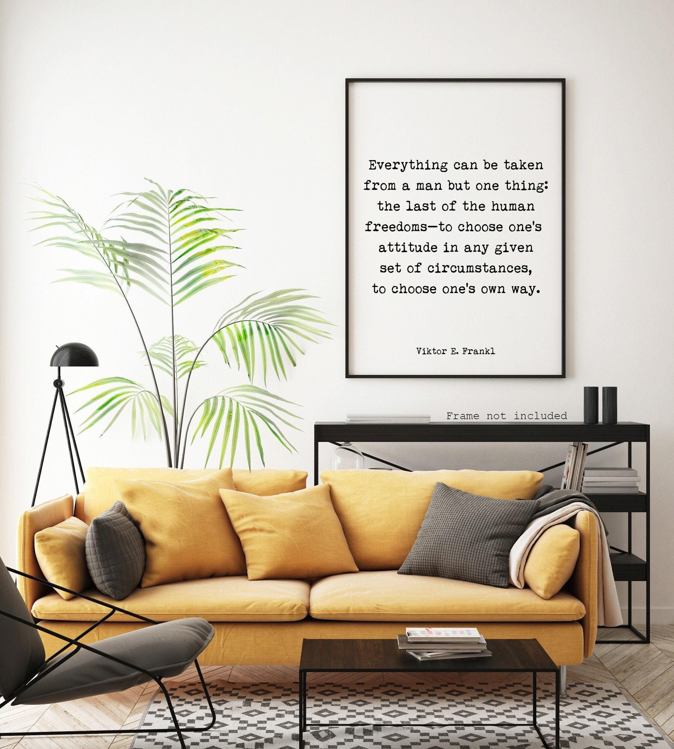 A white print with black text, "Everything can be taken from a man but one thing: the last of the human freedoms—to choose one's attitude in any given set of circumstances, to choose one's own way. Viktor E. Frankl," hangs on a white wall above a