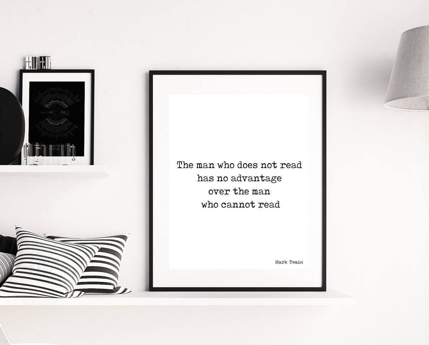 May include: A black and white typography print with the quote 'The man who does not read has no advantage over the man who cannot read' by Mark Twain. The print is framed in a black frame and is hanging on a white wall.