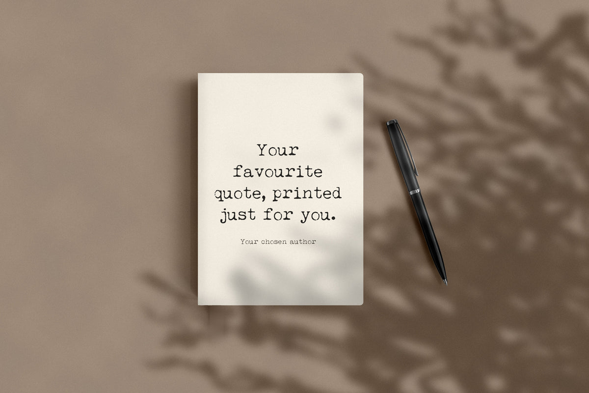 Custom quote journal lying flat beside a black pen