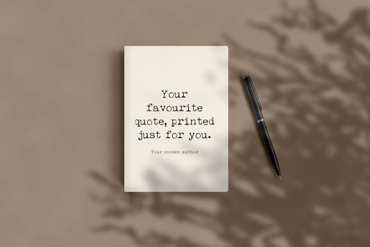 Custom quote journal lying flat beside a black pen