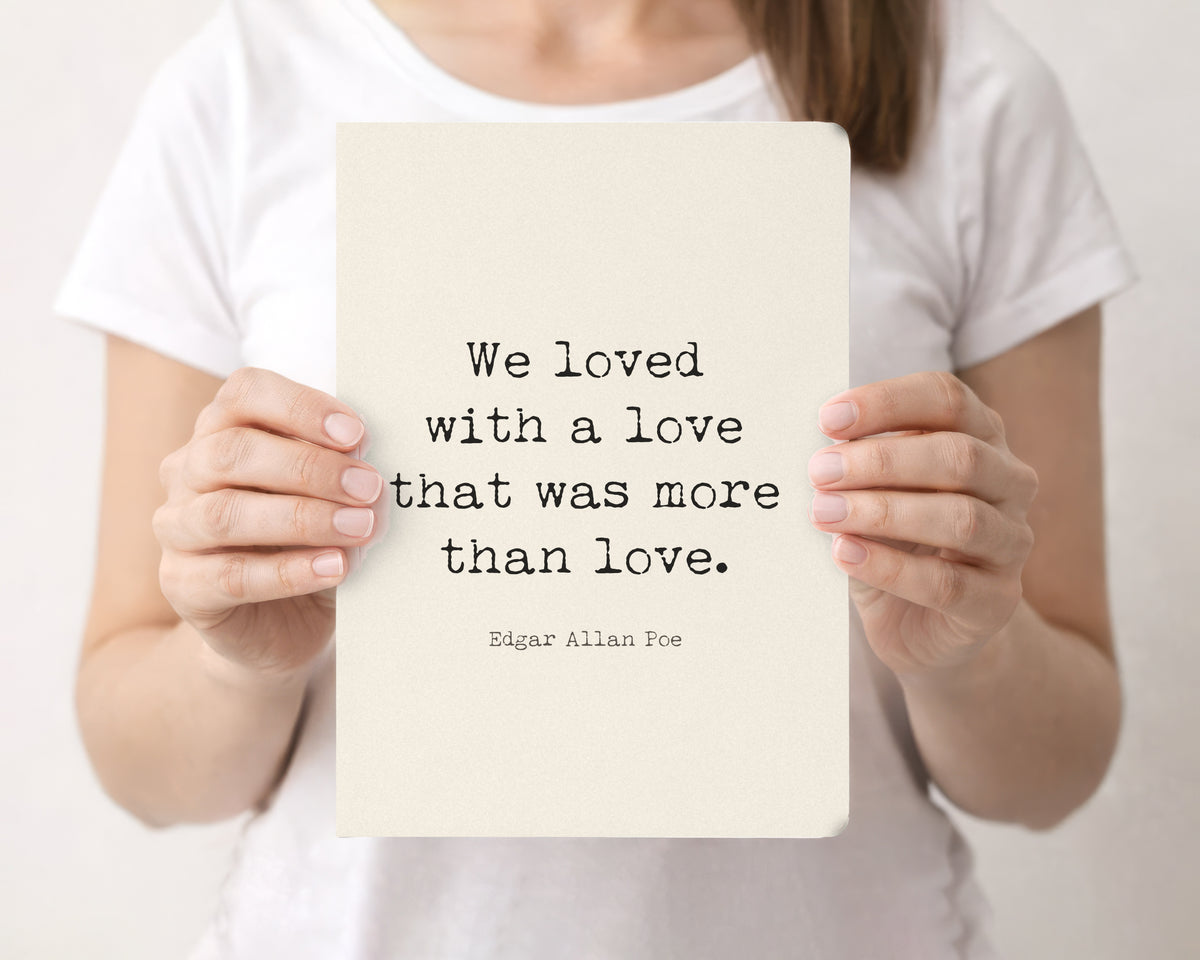 Woman holding a cream softcover journal with the Edgar Allan Poe We loved with a love quote on the front