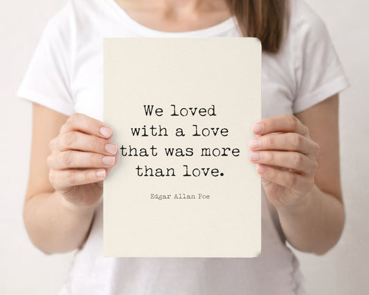 Woman holding a cream softcover journal with the Edgar Allan Poe We loved with a love quote on the front